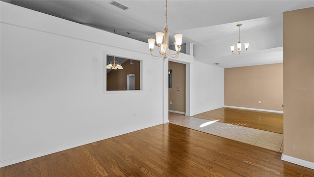 spare room with hardwood / wood-style floors and a chandelier