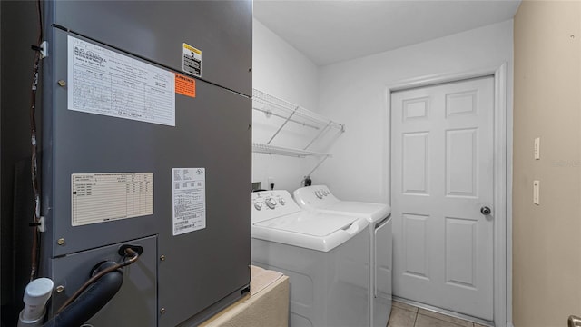 clothes washing area featuring heating unit, light tile patterned floors, and washing machine and clothes dryer