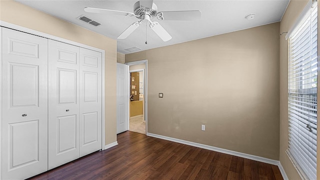 unfurnished bedroom with dark hardwood / wood-style flooring, a closet, and ceiling fan