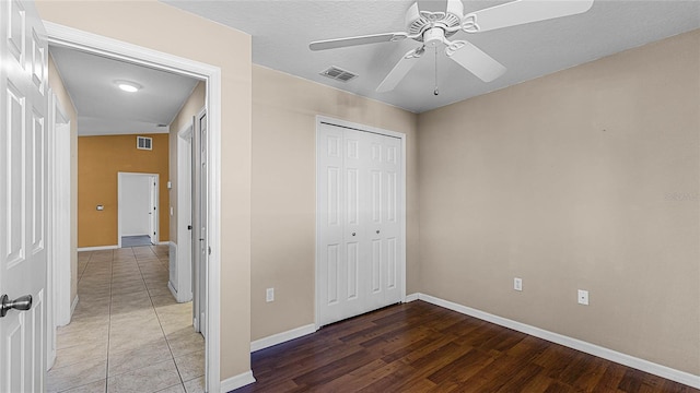 unfurnished bedroom featuring hardwood / wood-style floors, a textured ceiling, a closet, and ceiling fan