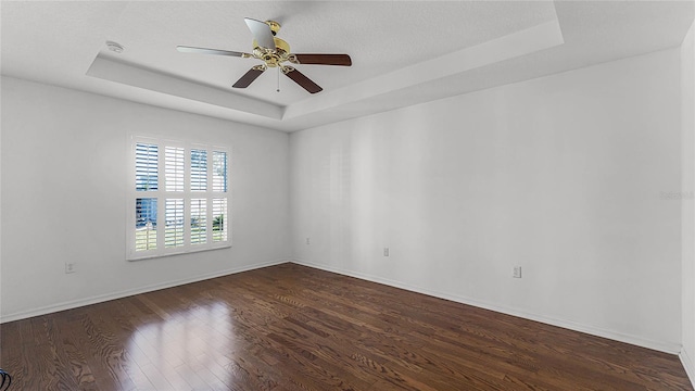 spare room featuring a tray ceiling, ceiling fan, a textured ceiling, and dark hardwood / wood-style floors