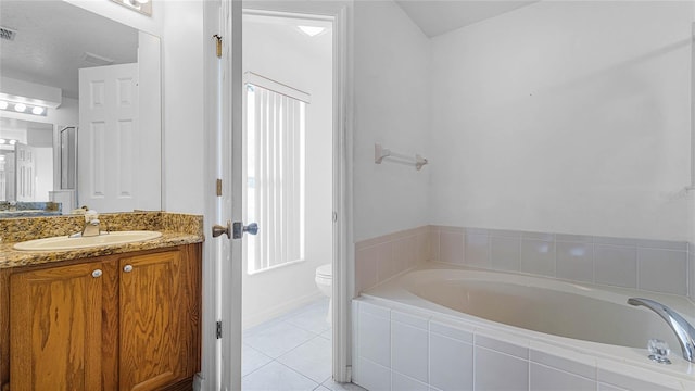 bathroom with tile patterned floors, tiled bath, vanity, and toilet