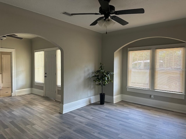 empty room with ceiling fan, a healthy amount of sunlight, light wood-type flooring, and a textured ceiling