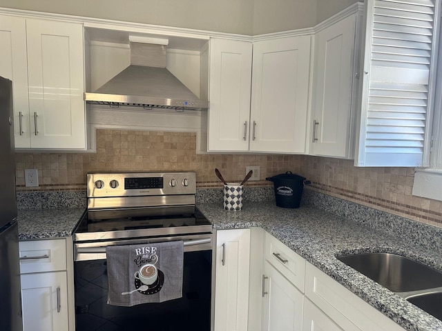 kitchen with decorative backsplash, white cabinetry, wall chimney range hood, and appliances with stainless steel finishes