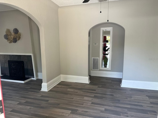 interior space featuring ceiling fan, a fireplace, and dark hardwood / wood-style floors