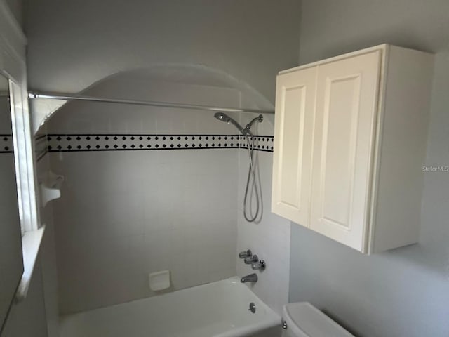 bathroom featuring tiled shower / bath combo and toilet