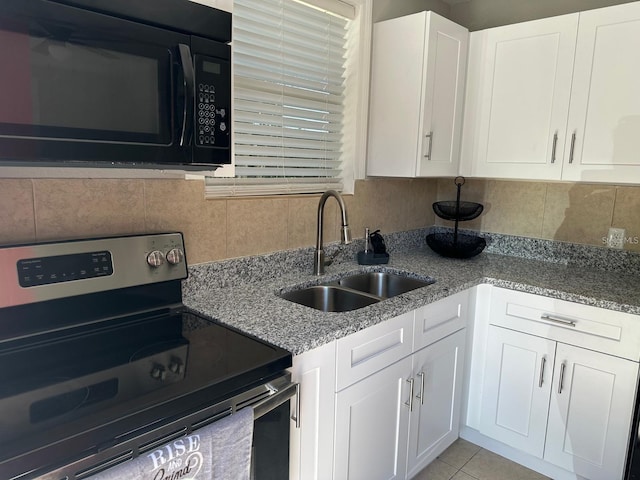 kitchen with sink, electric range, light stone countertops, light tile patterned floors, and white cabinetry