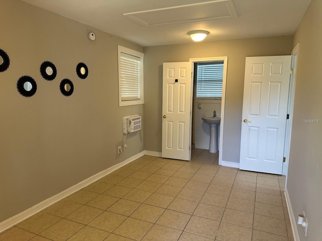 interior space with a wall mounted air conditioner, light tile patterned floors, and sink