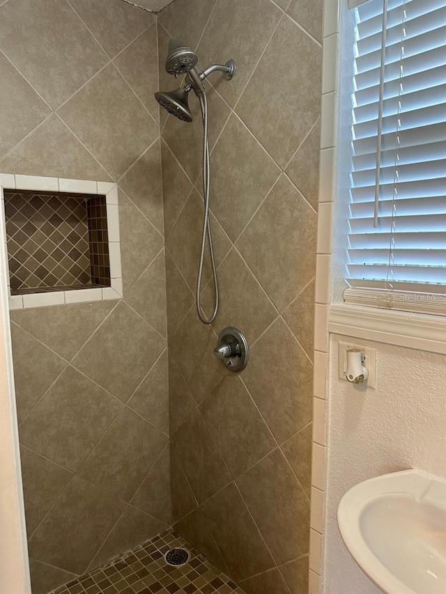 bathroom with a tile shower and sink