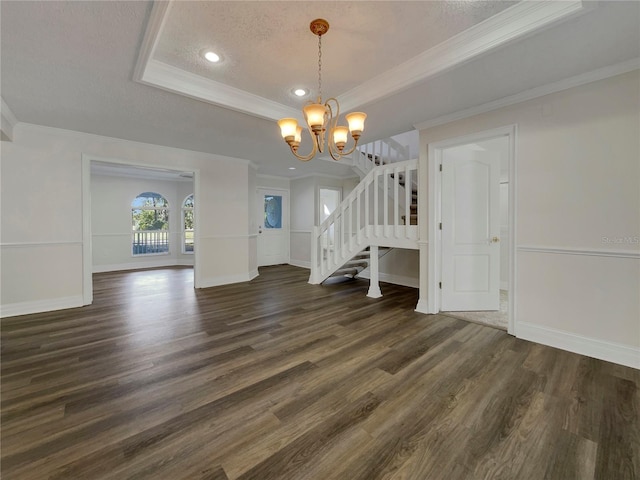 interior space with dark wood-type flooring, a raised ceiling, a notable chandelier, crown molding, and a textured ceiling