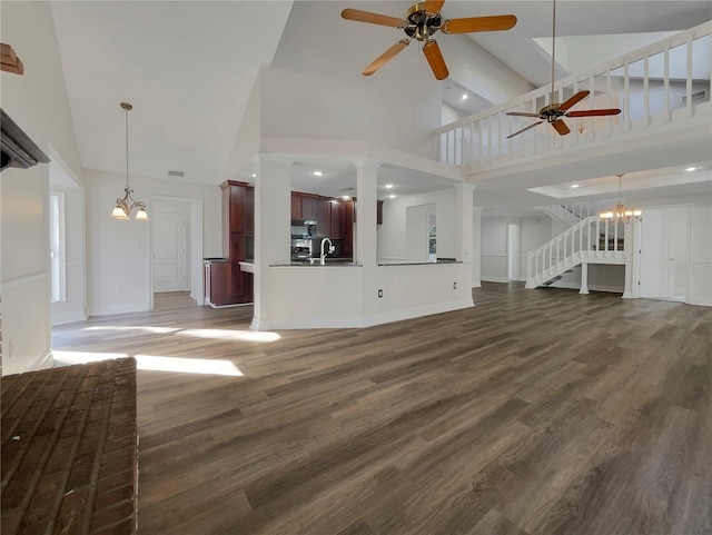 unfurnished living room featuring ceiling fan with notable chandelier, high vaulted ceiling, dark wood-type flooring, and sink