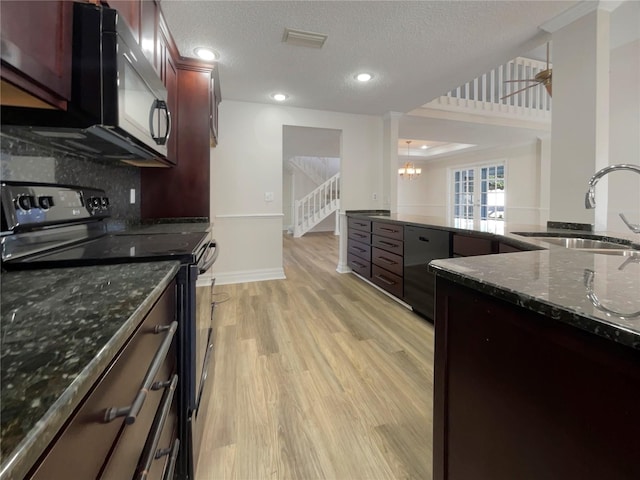 kitchen featuring black range with electric stovetop, sink, tasteful backsplash, dark stone countertops, and light wood-type flooring