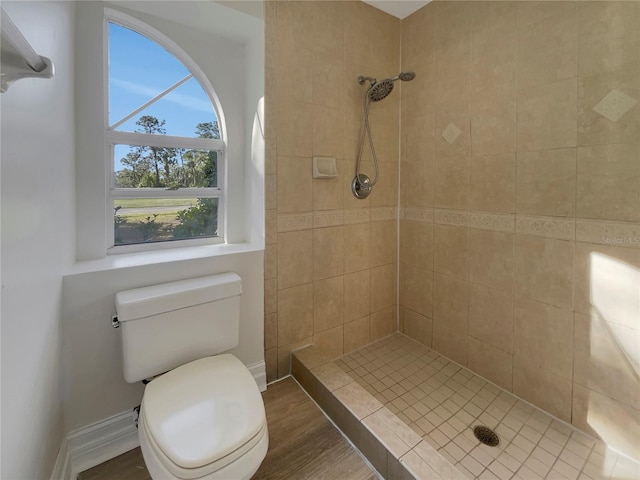 bathroom featuring tiled shower, hardwood / wood-style floors, and toilet