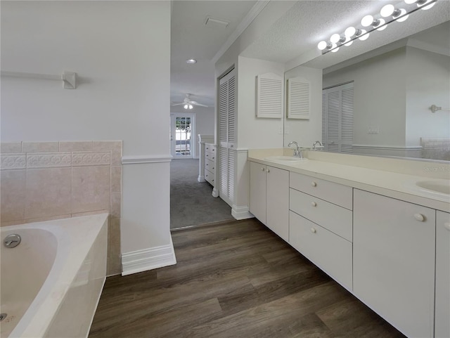 bathroom with hardwood / wood-style floors, vanity, ceiling fan, a textured ceiling, and a tub