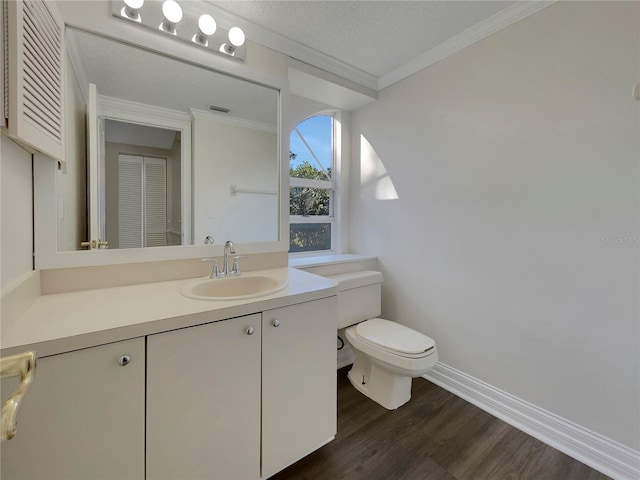 bathroom featuring ornamental molding, vanity, a textured ceiling, hardwood / wood-style floors, and toilet