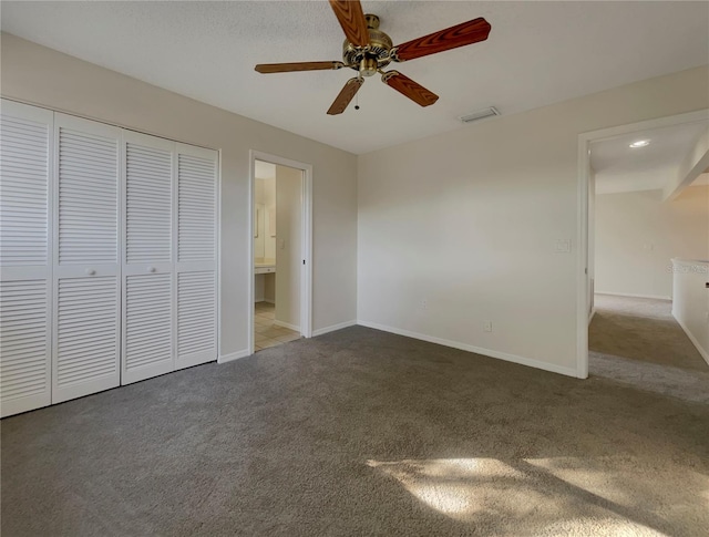 unfurnished bedroom featuring carpet, connected bathroom, a closet, and ceiling fan