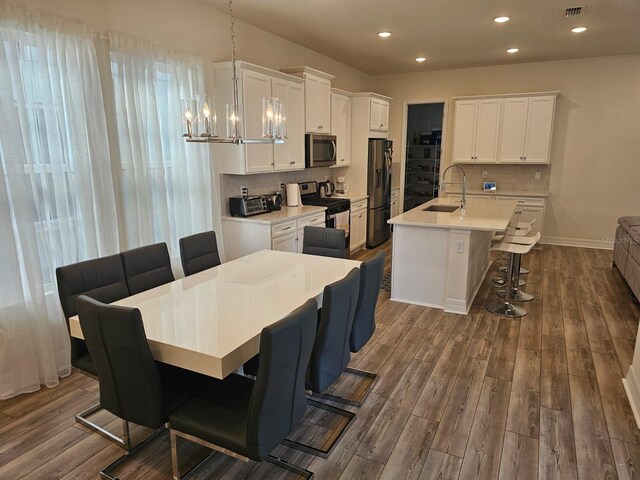 dining area with sink, dark hardwood / wood-style floors, and a notable chandelier