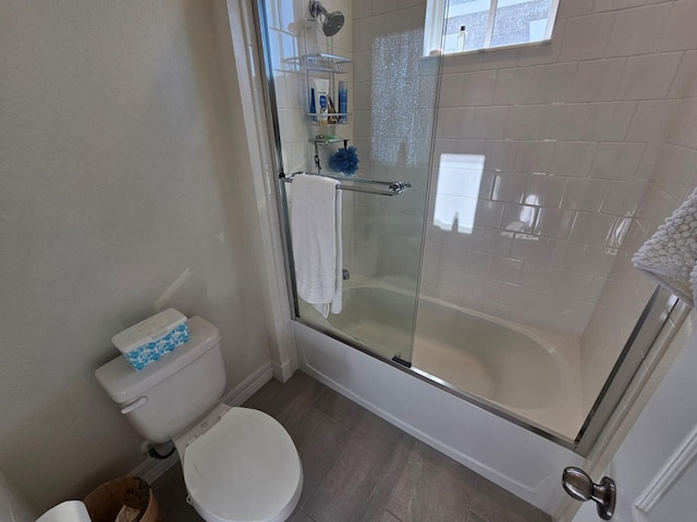 bathroom featuring hardwood / wood-style flooring, toilet, and bath / shower combo with glass door