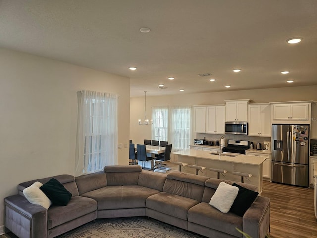 living room with a notable chandelier, dark wood-type flooring, and sink