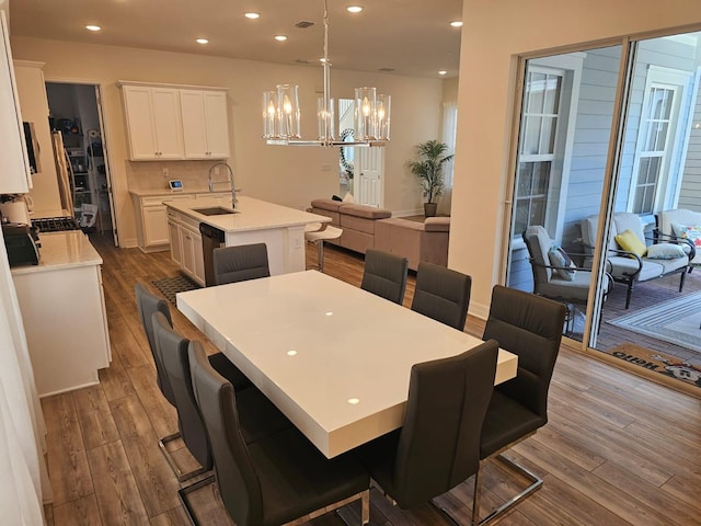 dining space with hardwood / wood-style floors, an inviting chandelier, and sink