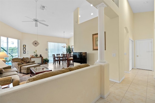 tiled living room featuring ceiling fan with notable chandelier, decorative columns, and high vaulted ceiling