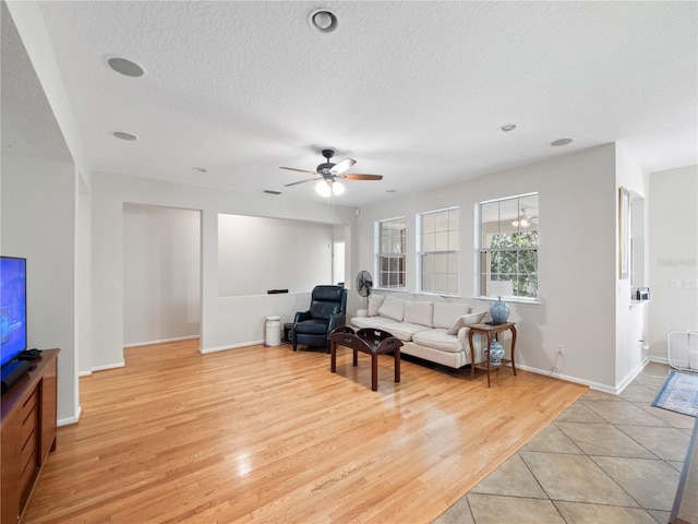 living room with a textured ceiling, light hardwood / wood-style floors, and ceiling fan