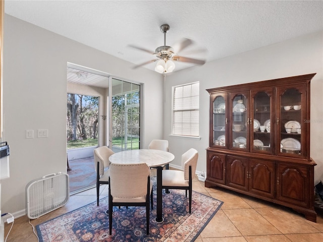 dining area featuring ceiling fan, light tile patterned floors, and a textured ceiling