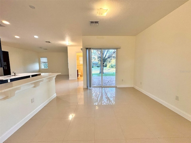 tiled empty room featuring sink and a textured ceiling