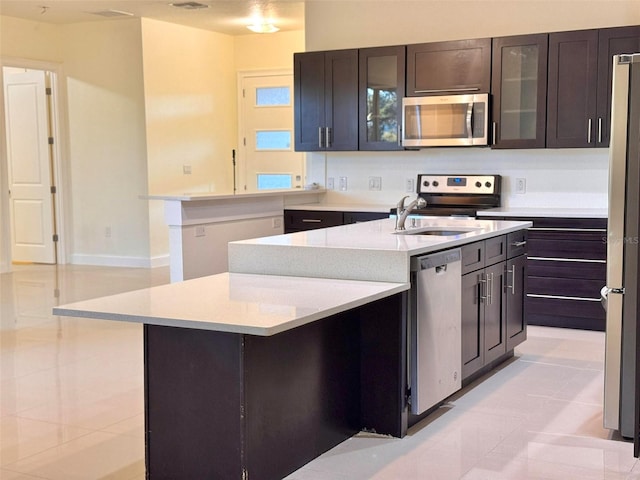 kitchen featuring light stone counters, stainless steel appliances, sink, an island with sink, and light tile patterned flooring