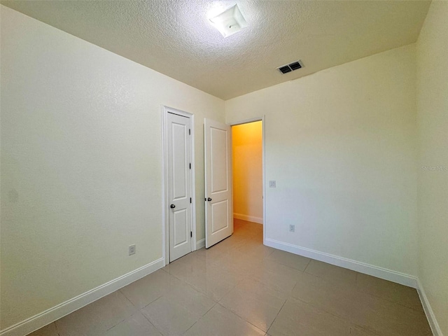 tiled spare room with a textured ceiling