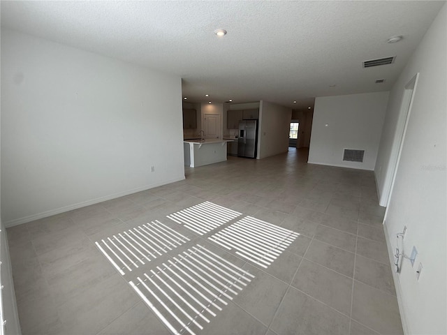 unfurnished living room featuring light tile patterned floors and a textured ceiling