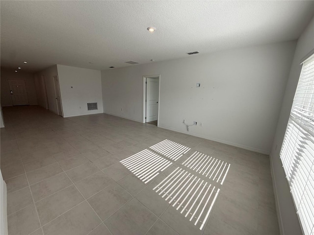 tiled empty room with a textured ceiling