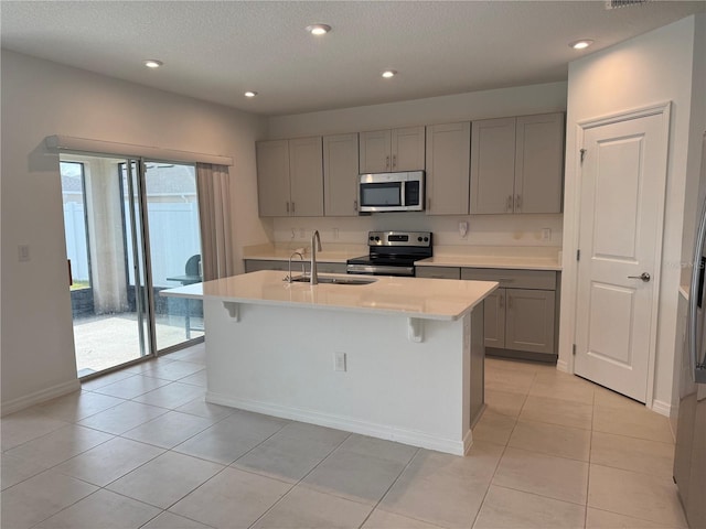 kitchen with sink, a center island with sink, gray cabinets, and appliances with stainless steel finishes