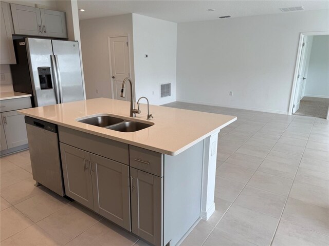 kitchen with sink, gray cabinets, stainless steel appliances, and an island with sink