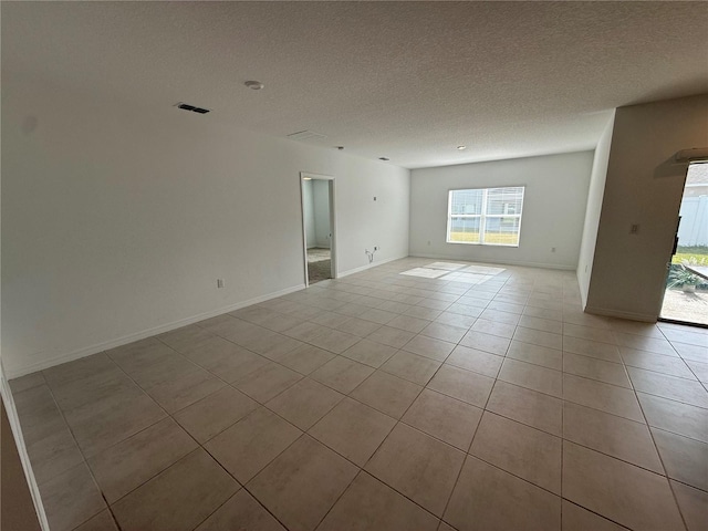 spare room with a textured ceiling and light tile patterned flooring