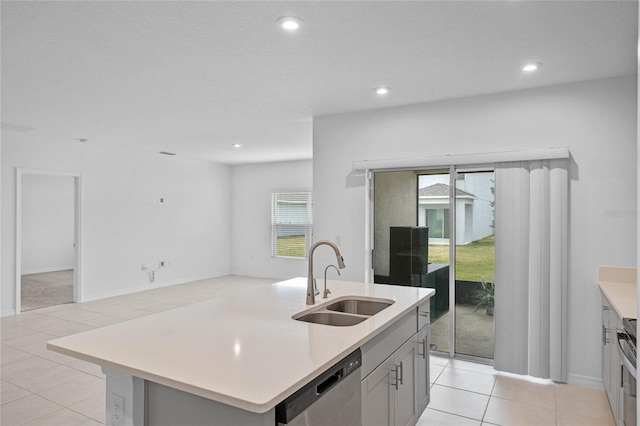 kitchen with sink, light tile patterned floors, gray cabinets, dishwasher, and a center island with sink