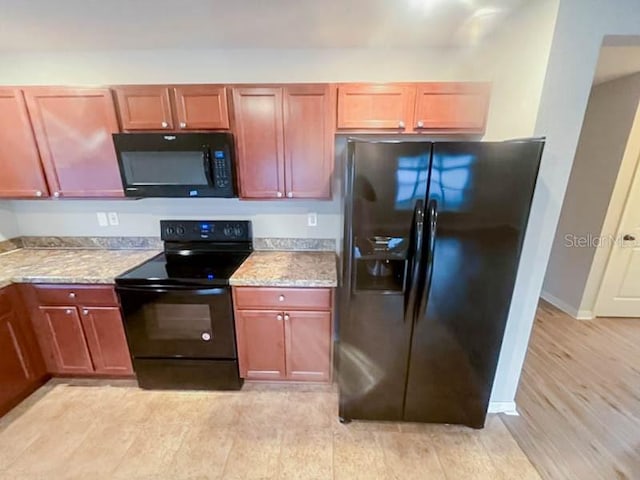 kitchen with light stone countertops, light hardwood / wood-style flooring, and black appliances