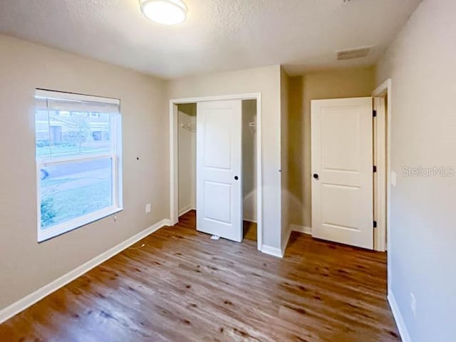 unfurnished bedroom with hardwood / wood-style floors, a textured ceiling, and a closet