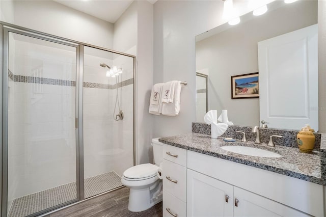 bathroom with toilet, vanity, a shower with door, and hardwood / wood-style flooring