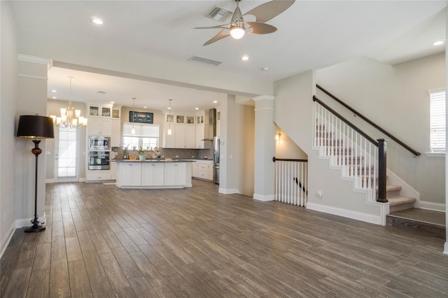 unfurnished living room with ceiling fan with notable chandelier and dark wood-type flooring