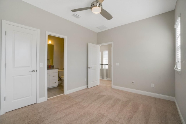 unfurnished bedroom featuring ceiling fan, light carpet, and ensuite bath