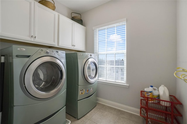 clothes washing area with cabinets, light tile patterned floors, and washing machine and dryer