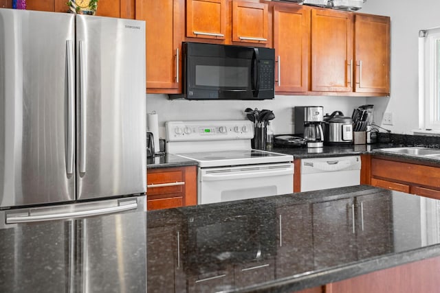 kitchen featuring white appliances, sink, and dark stone counters