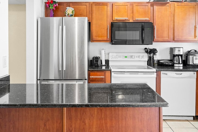 kitchen featuring dark stone countertops, white appliances, and light tile patterned floors