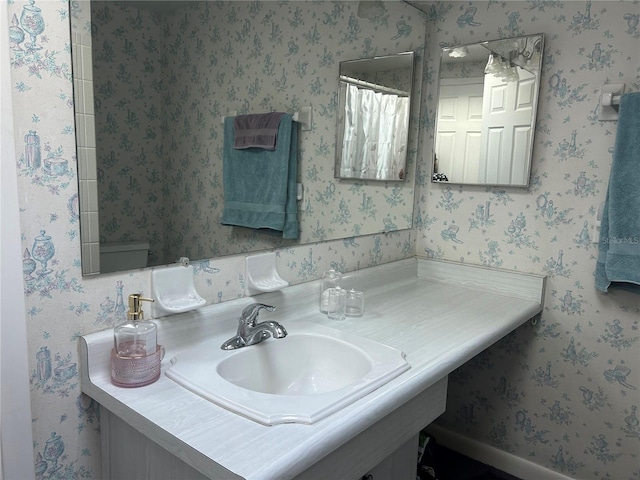 bathroom featuring sink, curtained shower, and toilet