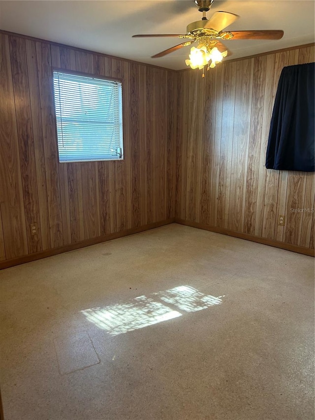 spare room featuring ceiling fan and wood walls