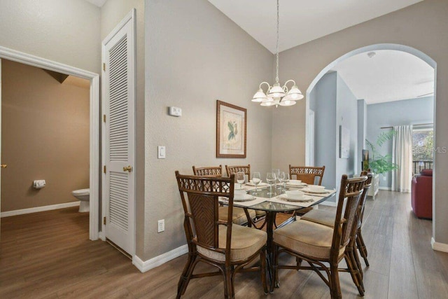 dining area with lofted ceiling, dark hardwood / wood-style floors, and a notable chandelier