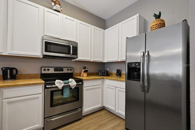 kitchen with appliances with stainless steel finishes, light hardwood / wood-style floors, and white cabinetry