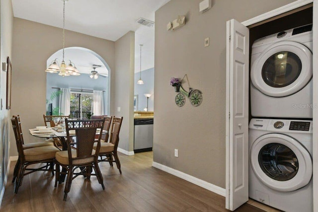 laundry area with ceiling fan with notable chandelier, dark hardwood / wood-style flooring, and stacked washing maching and dryer