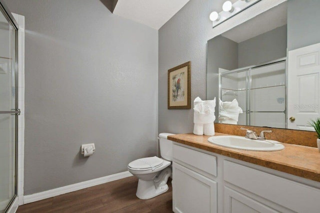 bathroom featuring hardwood / wood-style floors, vanity, toilet, and a shower with shower door